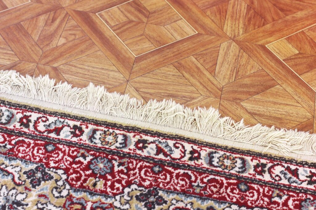 Close up of area rug with red border in open concept layout.